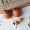 "GOOD EGG" micro stamp on two brown eggshells; black ink; small square stamp and farm carton in scene.