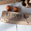 large wordmark and chicken icon stamped on kraft pulp egg carton; long layout across lid; black ink; farm packaging branding.